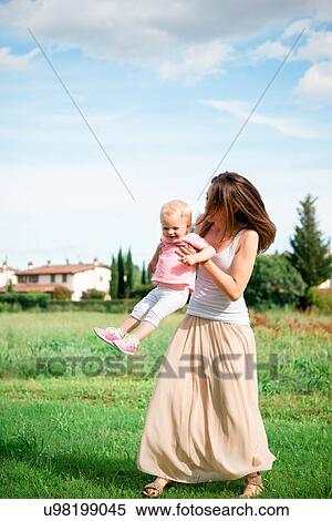 Stock Photography - Mother carrying toddler daughter in rural landscape, Arezzo, Tuscany, Italy. Fotosearch