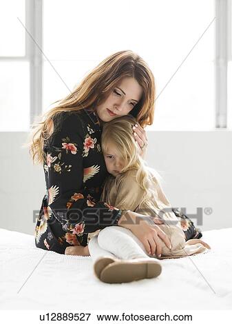 Stock Photo - Mother comforting her daughter on bed. Fotosearch