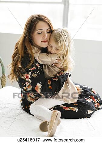 Mother comforting her daughter on bed View Large Photo Image Stock Photo - Mother comforting her daughter on bed. Fotosearch