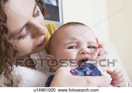 Mother holding crying baby girl View Large Photo Image Stock Image - Mother holding crying baby girl. Fotosearch
