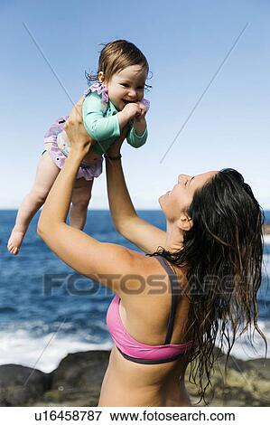 Mother holding her baby girl aloft by sea View Large Photo Image Stock Photo - Mother holding her baby girl aloft by sea. Fotosearch