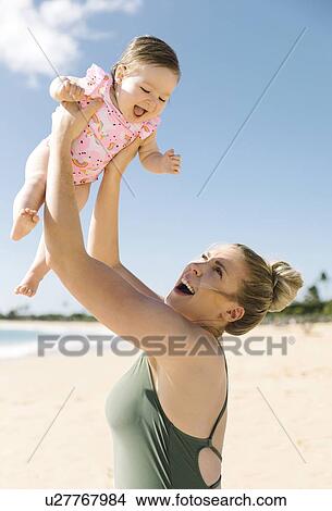 Mother holding her baby girl aloft on beach View Large Photo Image Picture - Mother holding her baby girl aloft on beach. Fotosearch