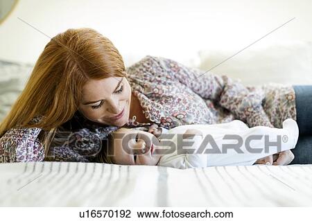 Stock Image - Mother lying on bed with her newborn son. Fotosearch