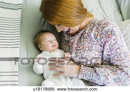 Stock Photography - Mother lying on bed with her newborn son. Fotosearch