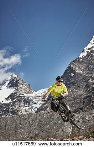 Stock Photo - Mountain biker jumping, Saas-Fee, Valais, Switzerland. Fotosearch