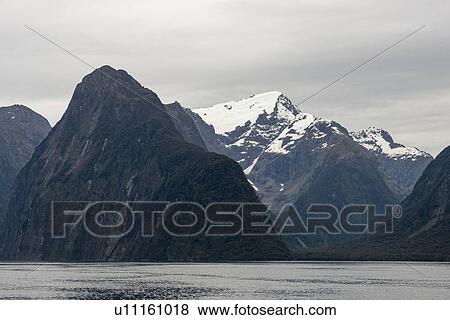 Stock Photo - Mountains by sea in Milford Sound, New Zealand. Fotosearch
