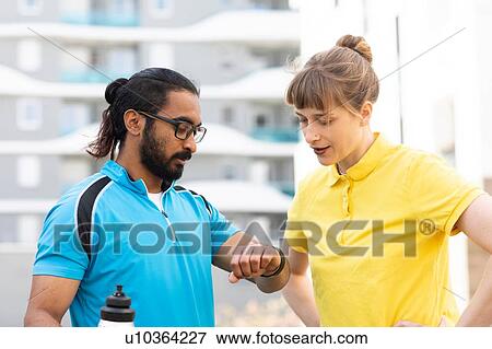 Multi-ethnic couple checking time after exercise View Large Photo Image Stock Photo - Multi-ethnic couple checking time after exercise. Fotosearch