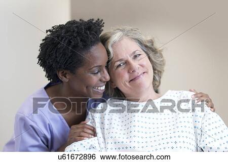 Stock Photograph - Nurse comforting female patient, smiling.. Fotosearch
