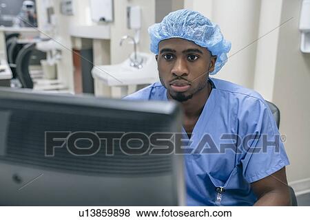 Stock Photo - Nurse wearing hair net using computer in hospital. Fotosearch