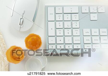 Stock Photography - Open pill bottles by computer keyboard and mouse. Fotosearch