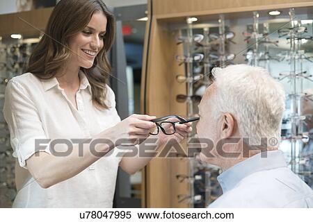 Optician putting glasses on senior man. View Large Photo Image Stock Photography - Optician putting glasses on senior man.. Fotosearch