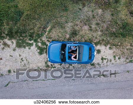 Stock Photograph - Overhead view of friends talking inside car by roadside. Fotosearch