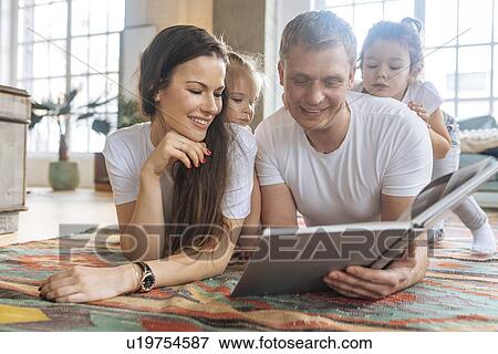 Stock Photo - Parents and daughters reading picture book. Fotosearch