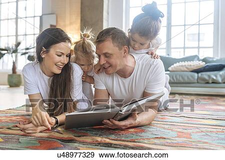 Stock Photo - Parents and daughters reading picture book. Fotosearch