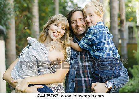 Stock Image - Parents holding their sons in garden. Fotosearch
