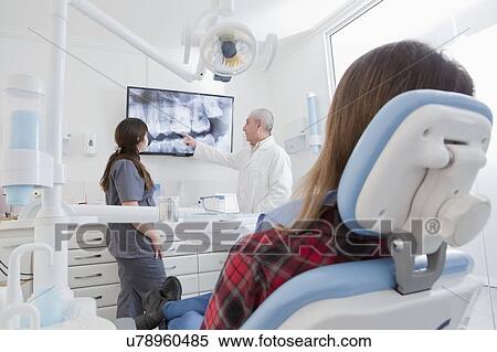Stock Photography - Patient by dentist examining X-ray of teeth. Fotosearch