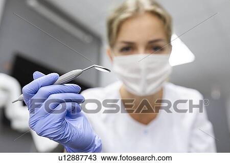 Stock Image - Patient point of view of dental assistant holding dental equipment. Fotosearch