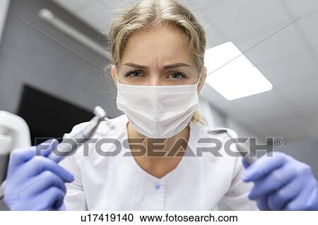 Patient point of view of dental assistant holding dental equipment View Large Photo Image Stock Image - Patient point of view of dental assistant holding dental equipment. Fotosearch