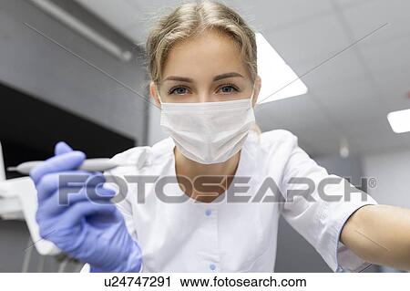 Patient point of view of dental assistant holding dental equipment View Large Photo Image Stock Image - Patient point of view of dental assistant holding dental equipment. Fotosearch