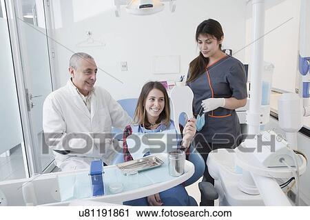 Patient smiling at mirror in dentist's surgery View Large Photo Image Stock Image - Patient smiling at mirror in dentist's surgery. Fotosearch