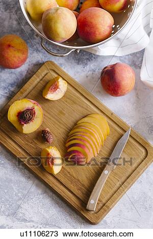 Stock Image - Peaches sliced on wooden cutting board. Fotosearch