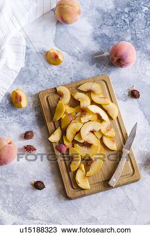 Stock Image - Peaches sliced on wooden cutting board. Fotosearch