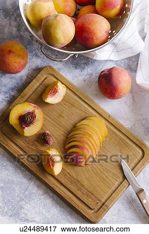 Peaches sliced on wooden cutting board View Large Photo Image Stock Photo - Peaches sliced on wooden cutting board. Fotosearch