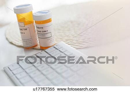 Stock Photography - Pill bottles by computer keyboard. Fotosearch