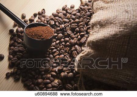 Stock Photo - Portafilter holding ground coffee on roasted coffee beans. Fotosearch