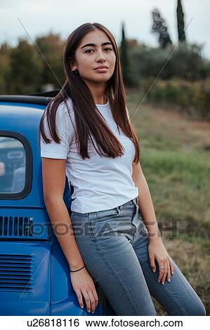 Stock Photograph - Portrait of woman leaning against car in countryside, Florence, Toscana, Italy. Fotosearch
