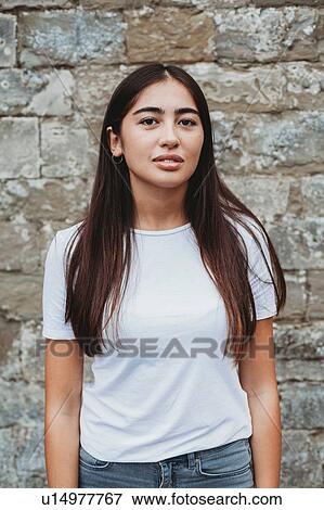 Stock Photo - Portrait of young woman against stonewall. Fotosearch