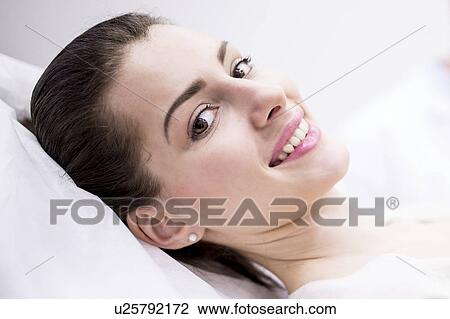 Stock Image - Portrait of young woman lying on couch in clinic.. Fotosearch