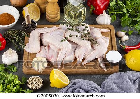 Stock Image - Raw chicken on cutting board surrounded by ingredients. Fotosearch
