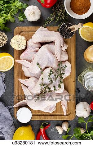 Stock Image - Raw chicken on cutting board surrounded by ingredients. Fotosearch