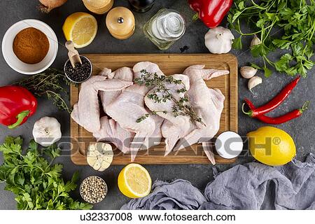 Raw chicken on cutting board surrounded by ingredients View Large Photo Image Stock Photo - Raw chicken on cutting board surrounded by ingredients. Fotosearch
