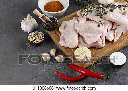 Stock Photo - Raw chicken on cutting board with herb and spices. Fotosearch