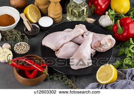 Stock Image - Raw chicken on plate surrounded by ingredients. Fotosearch