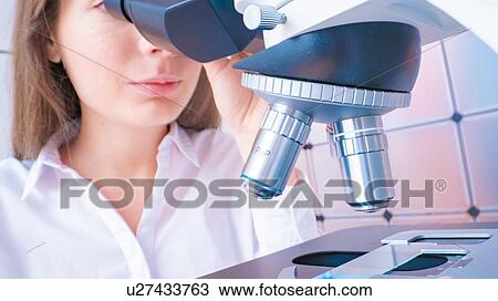 Stock Image - Researcher using microscope.. Fotosearch