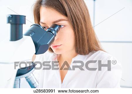 Stock Image - Researcher using microscope.. Fotosearch