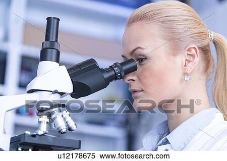 Stock Photography - Researcher using microscope.. Fotosearch