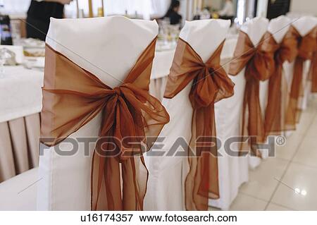 Stock Photo - Ribbon tied to dining chairs at wedding. Fotosearch