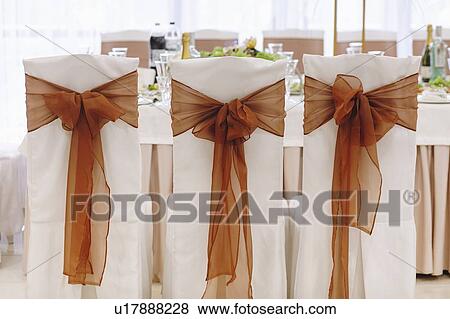Ribbon tied to dining chairs at wedding View Large Photo Image Stock Photo - Ribbon tied to dining chairs at wedding. Fotosearch