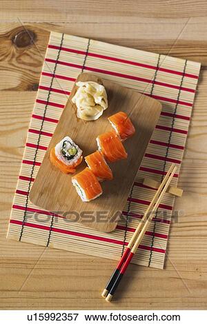Stock Photo - Salmon sushi on cutting board with chopsticks and mat. Fotosearch