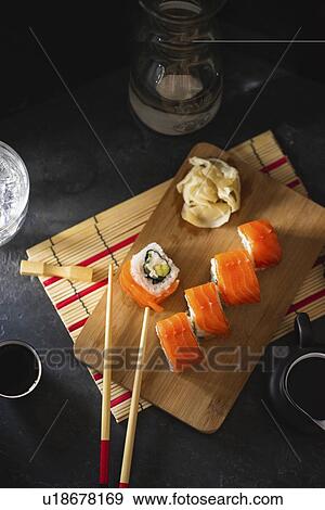 Stock Photo - Salmon sushi on cutting board with pickled ginger and chopsticks. Fotosearch