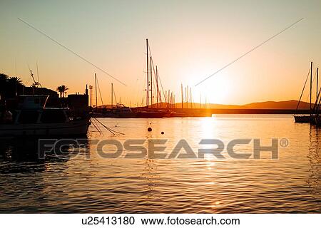 Stock Image - Scenic view of yachts in marina at sunset, Alghero, Sardinia, Italy. Fotosearch