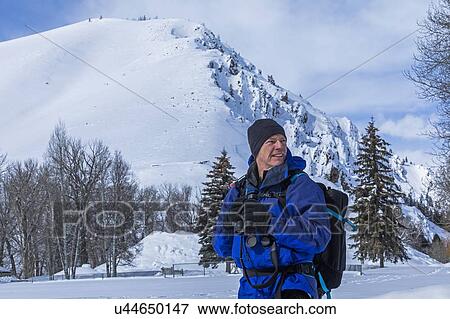 Senior man holding binoculars by snow covered mountain in Sun Valley, Idaho, USA View Large Photo Image Stock Photo - Senior man holding binoculars by snow covered mountain in Sun Valley, Idaho, USA. Fotosearch