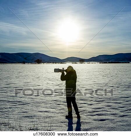 Stock Image - Senior man photographing in snow field in Picabo, Idaho. Fotosearch