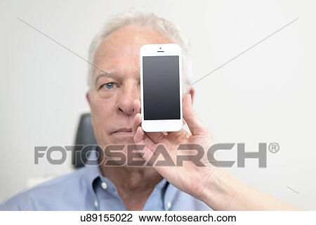 Senior man with smartphone covering eye. View Large Photo Image Stock Image - Senior man with smartphone covering eye.. Fotosearch