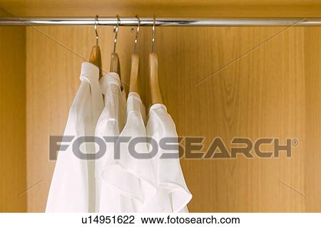 Stock Image - Shirts on clothes hangers in wardrobe. Fotosearch