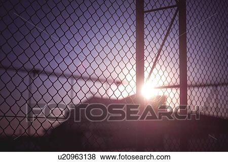 Stock Photo - Silhouette of building behind wire fence.. Fotosearch